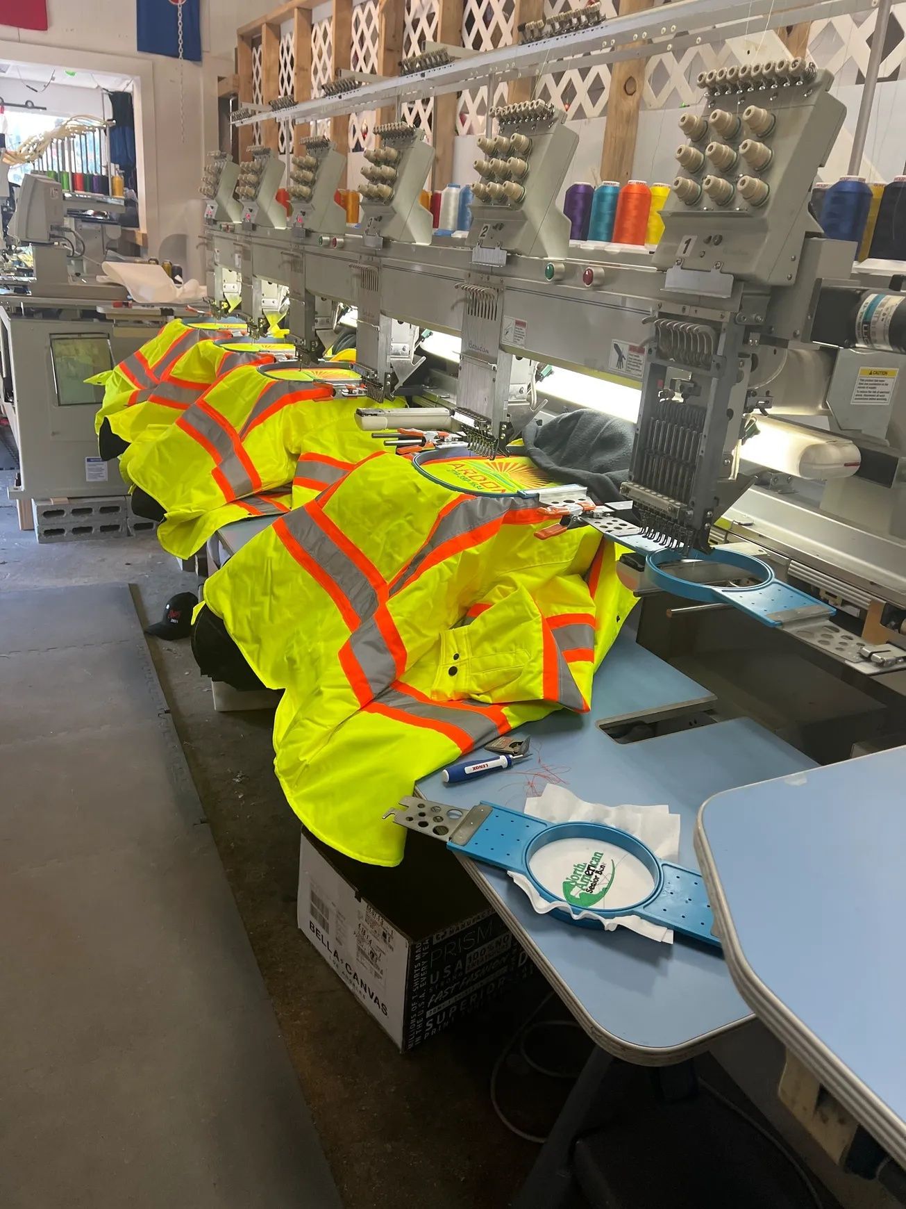 Hi-vis safety vests being sewn on an industrial embroidery machine in a workshop