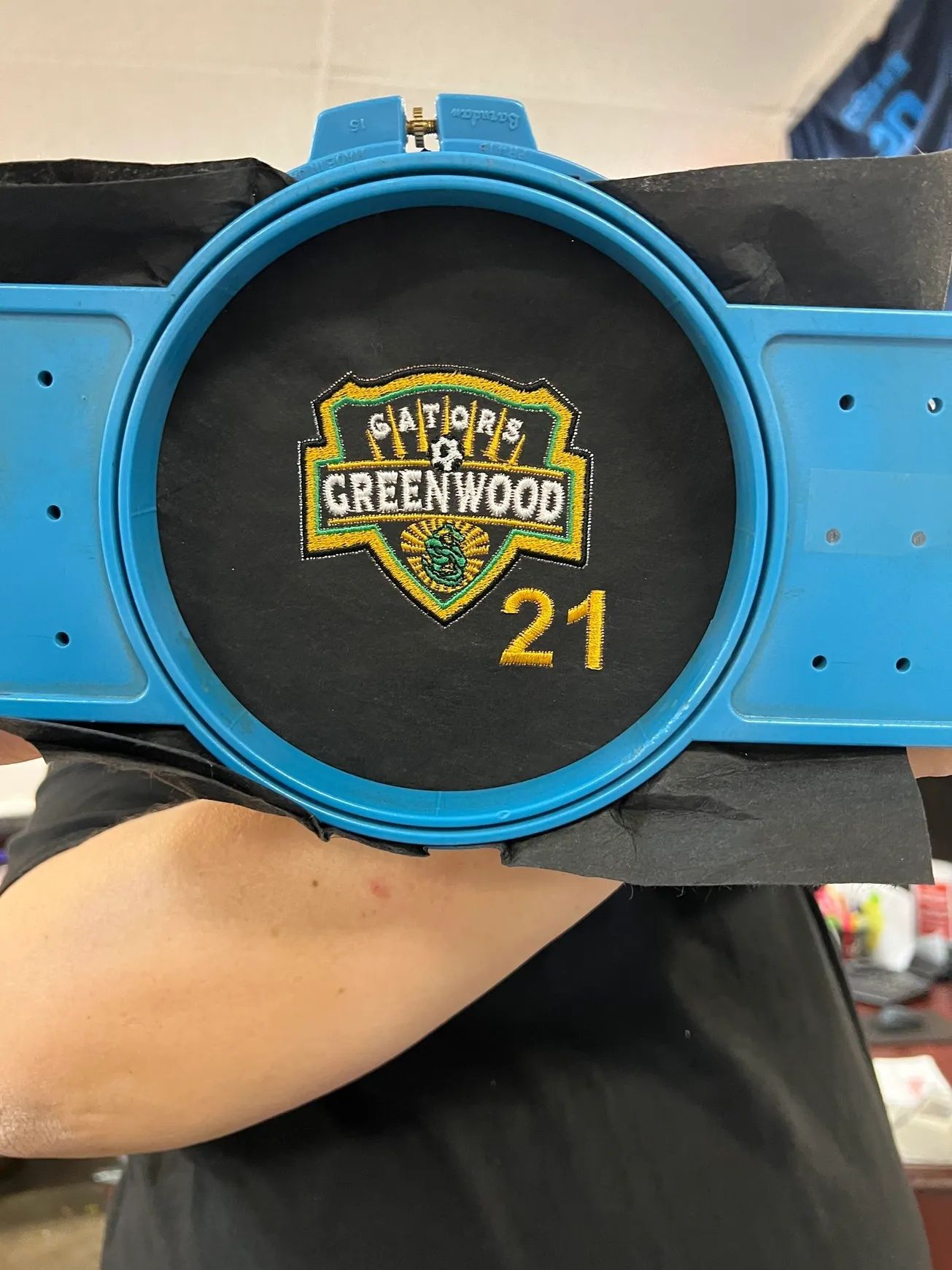 Blue toy car front with Greenwood logo and number 21 held in someone's hands