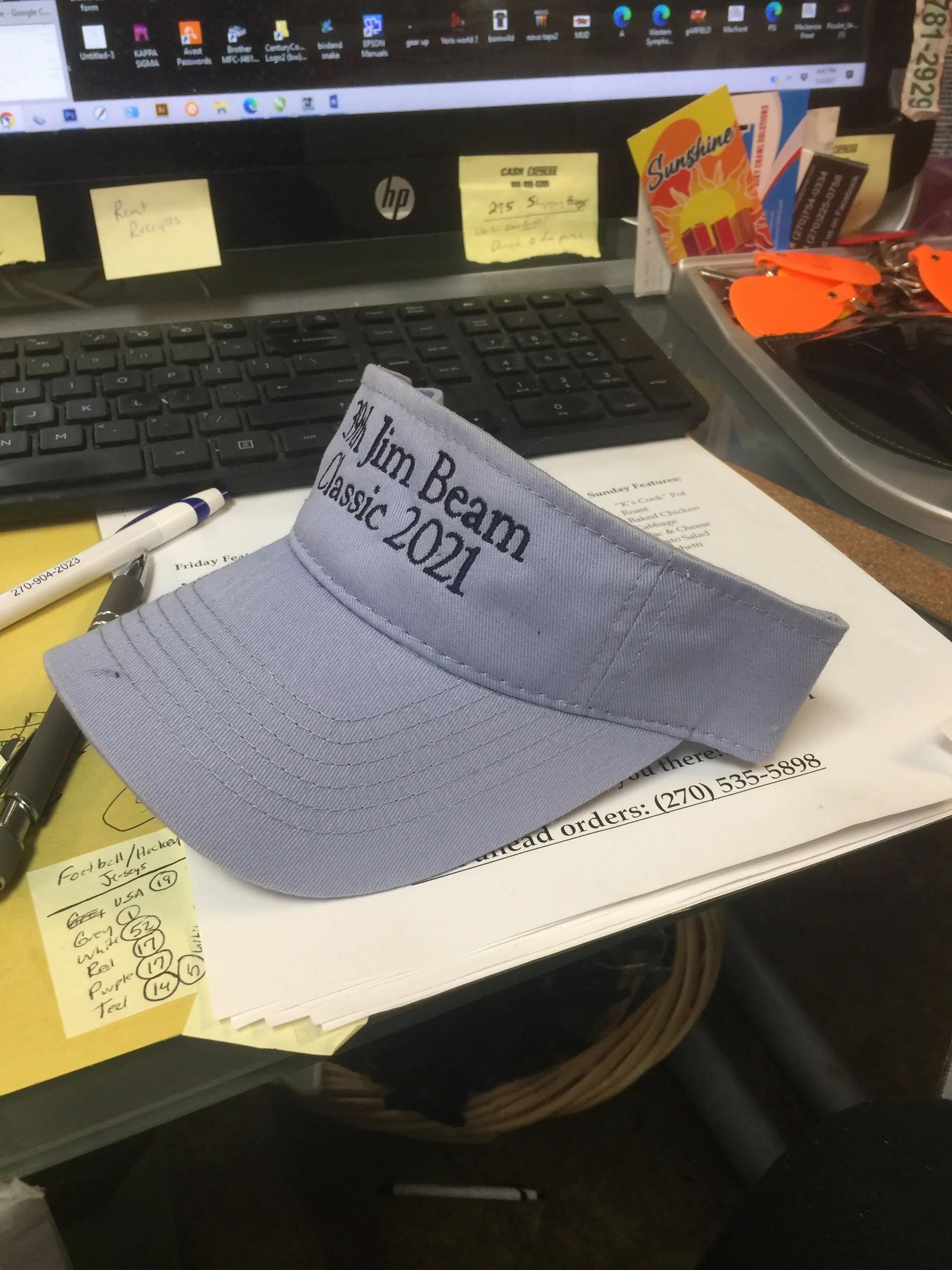 Desk with laptop, papers, and a blue embroidered cap reading “I’m Bean Class of 2021.”