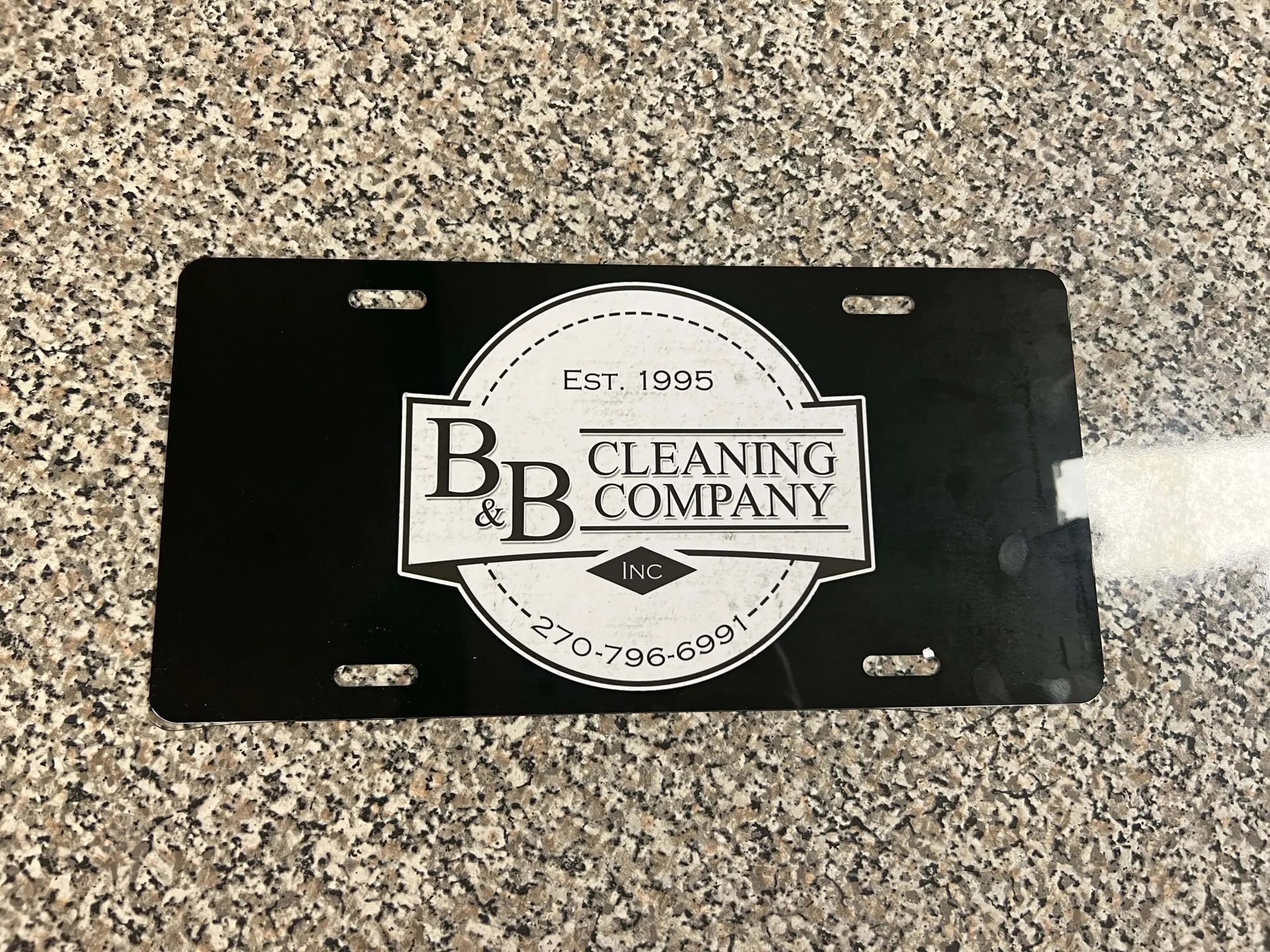 Black cleaning company nameplate on speckled countertop.