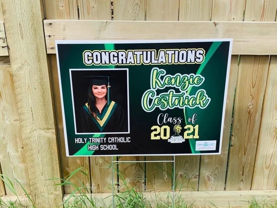 Graduation sign with photo and “Congratulations,” “Class of 20-21” on wooden fence