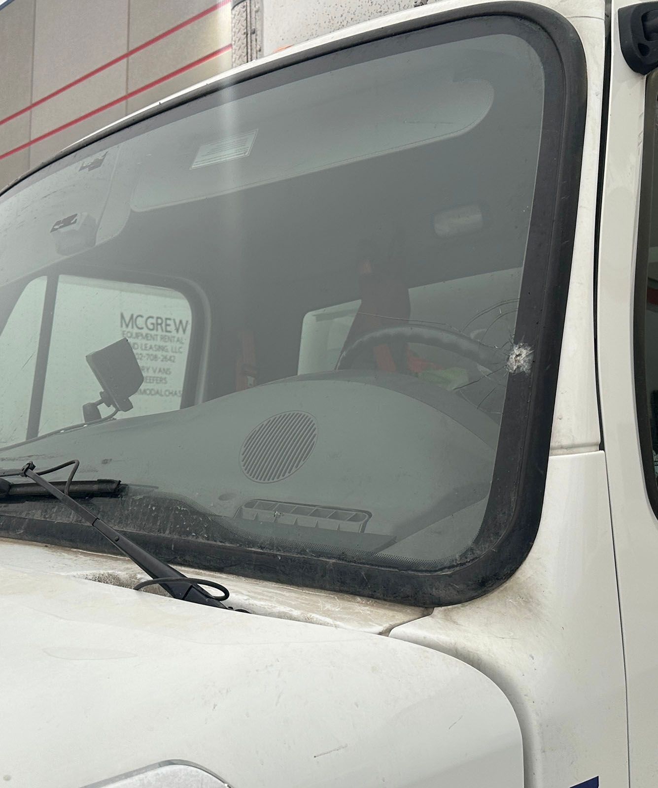 White truck windshield with black trim and wipers. Interior shows dashboard and driver's seat.