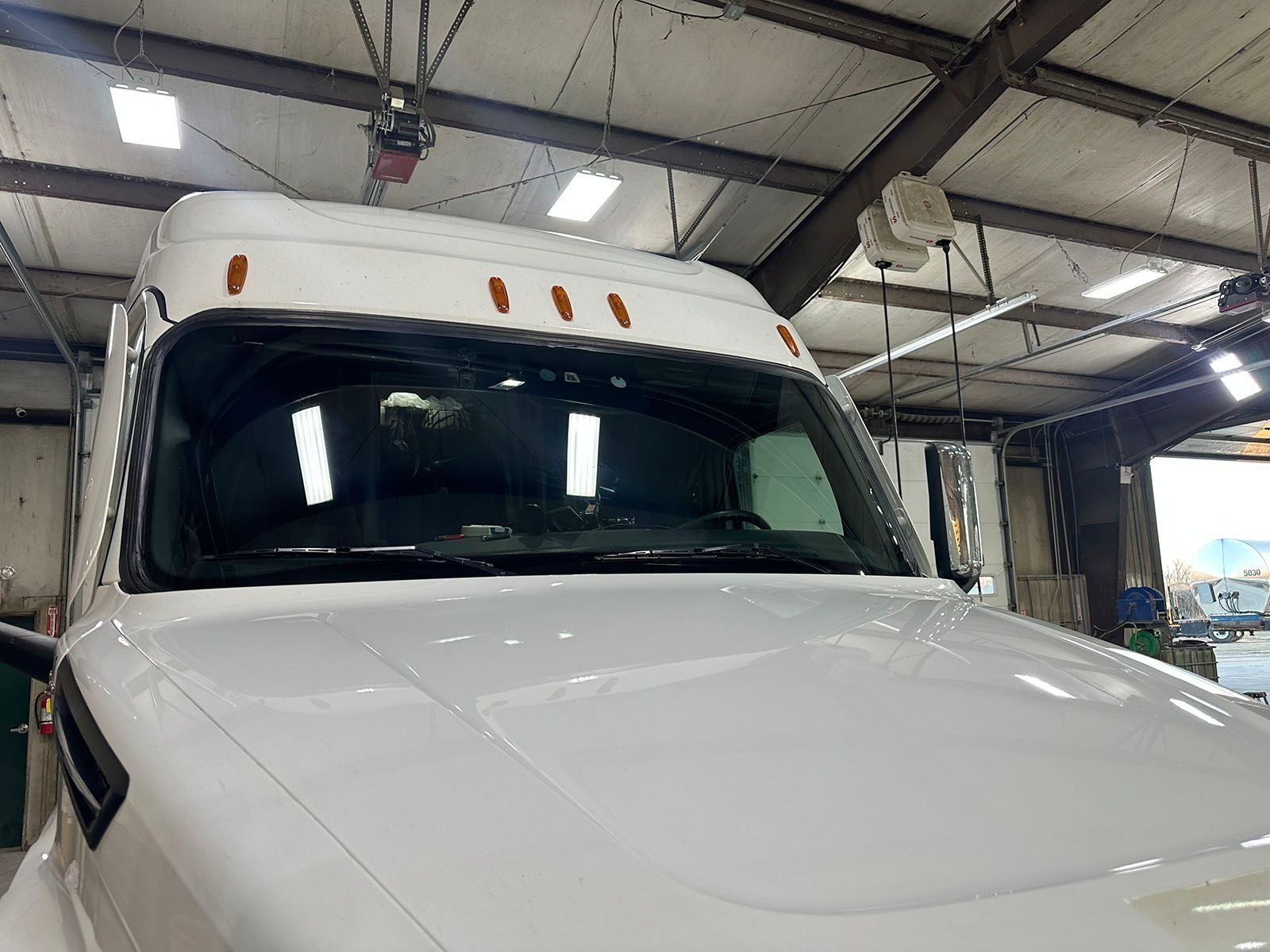 White semi-truck cab in a garage. Front view with lights on top.