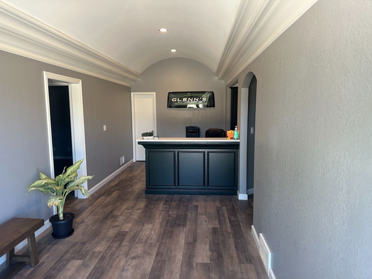 Reception area with dark wood floors, gray walls, white trim, and a black counter.