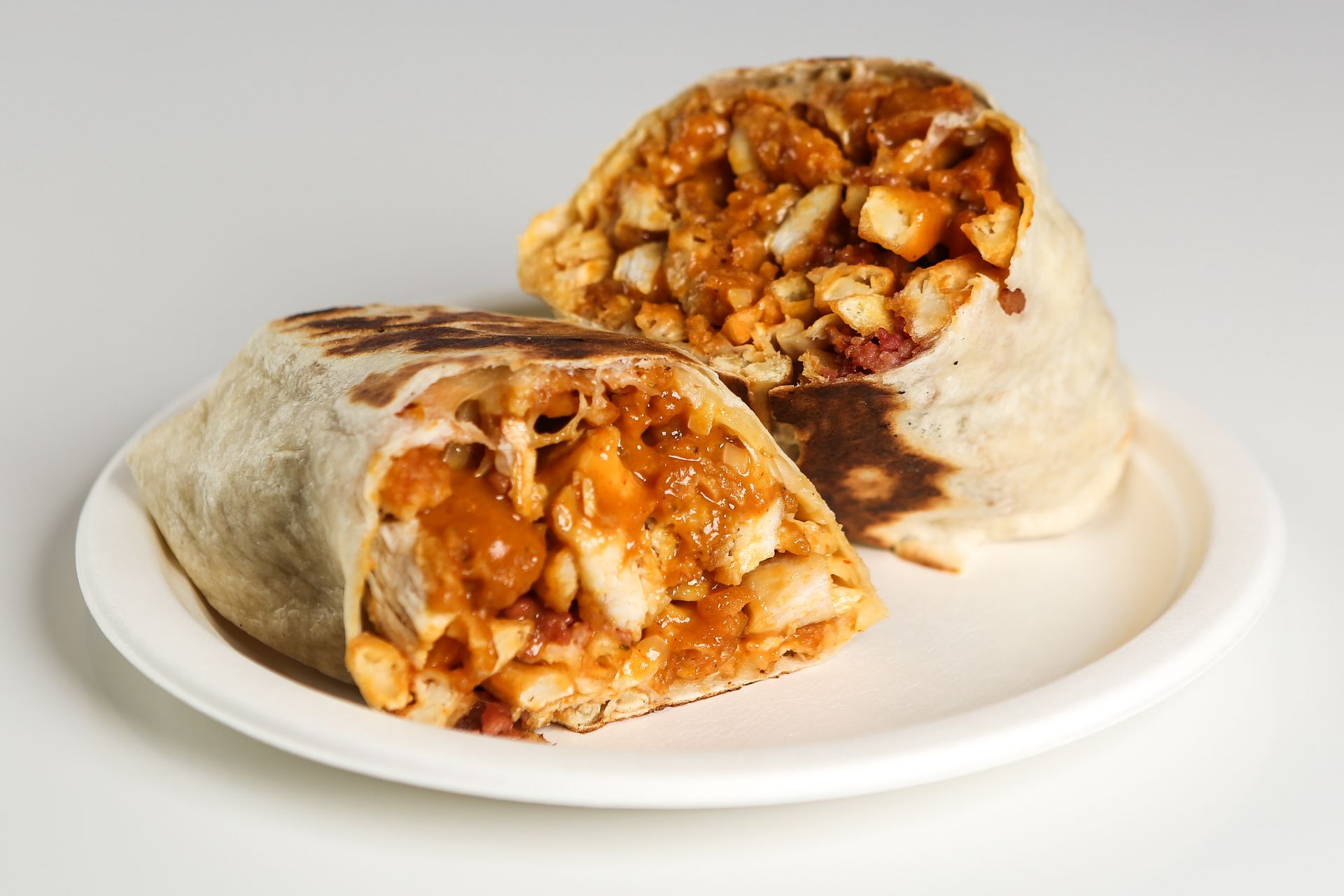 Two burritos are cut in half on a white plate.