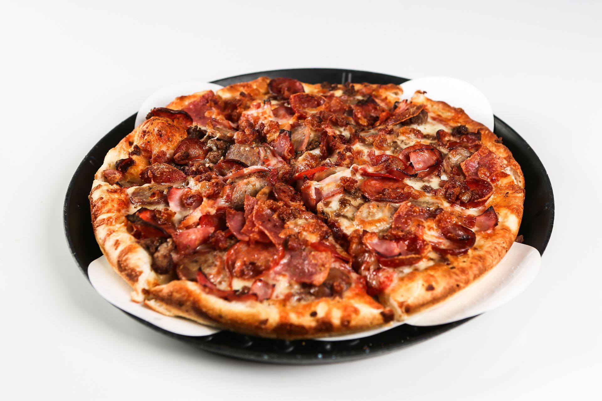 A pizza with a slice taken out of it is on a black and white plate.