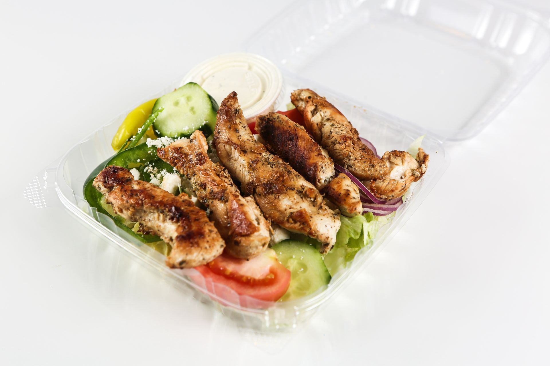 A plastic container filled with chicken and vegetables on a table.