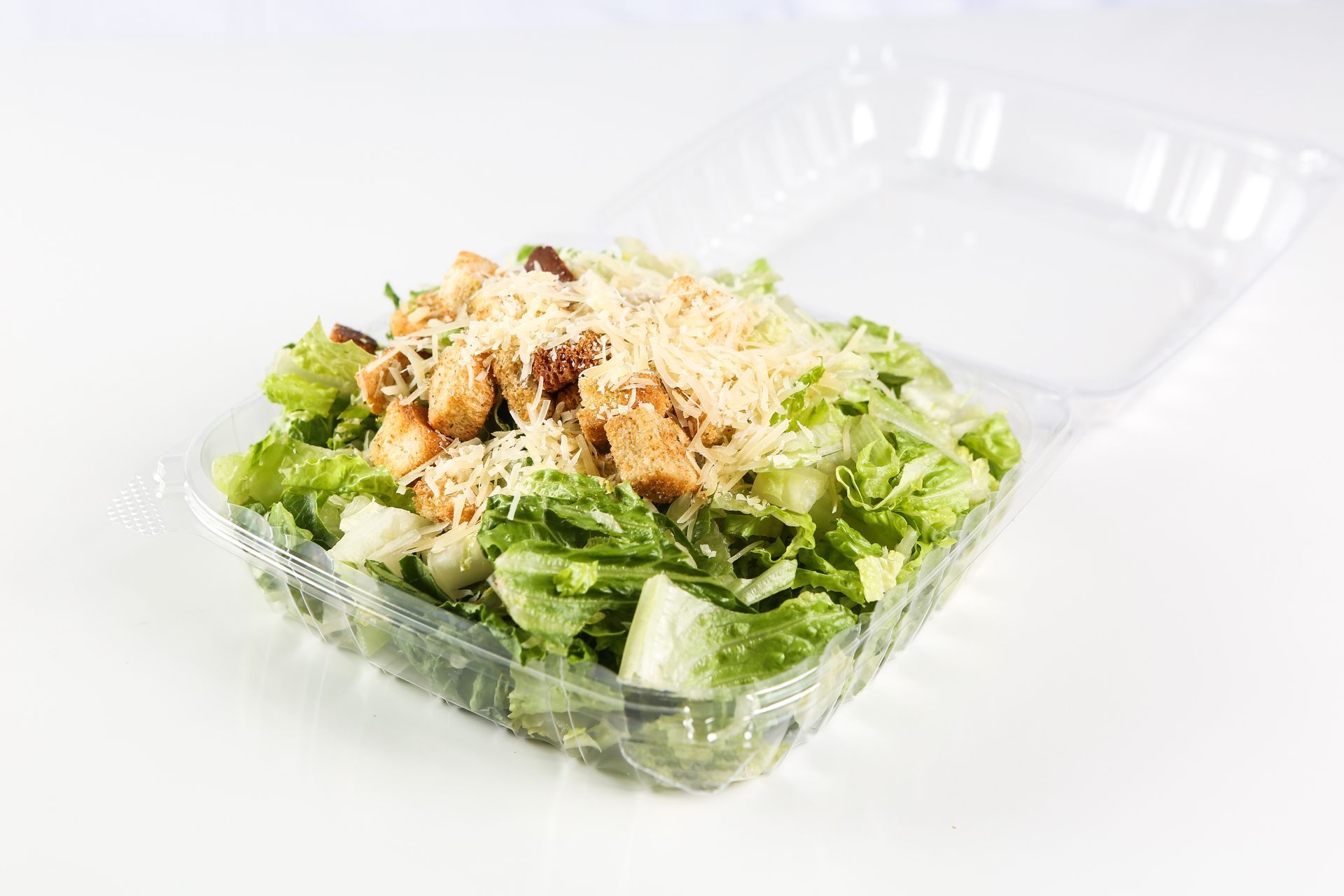 A close-up of a salad in a plastic container on a table.