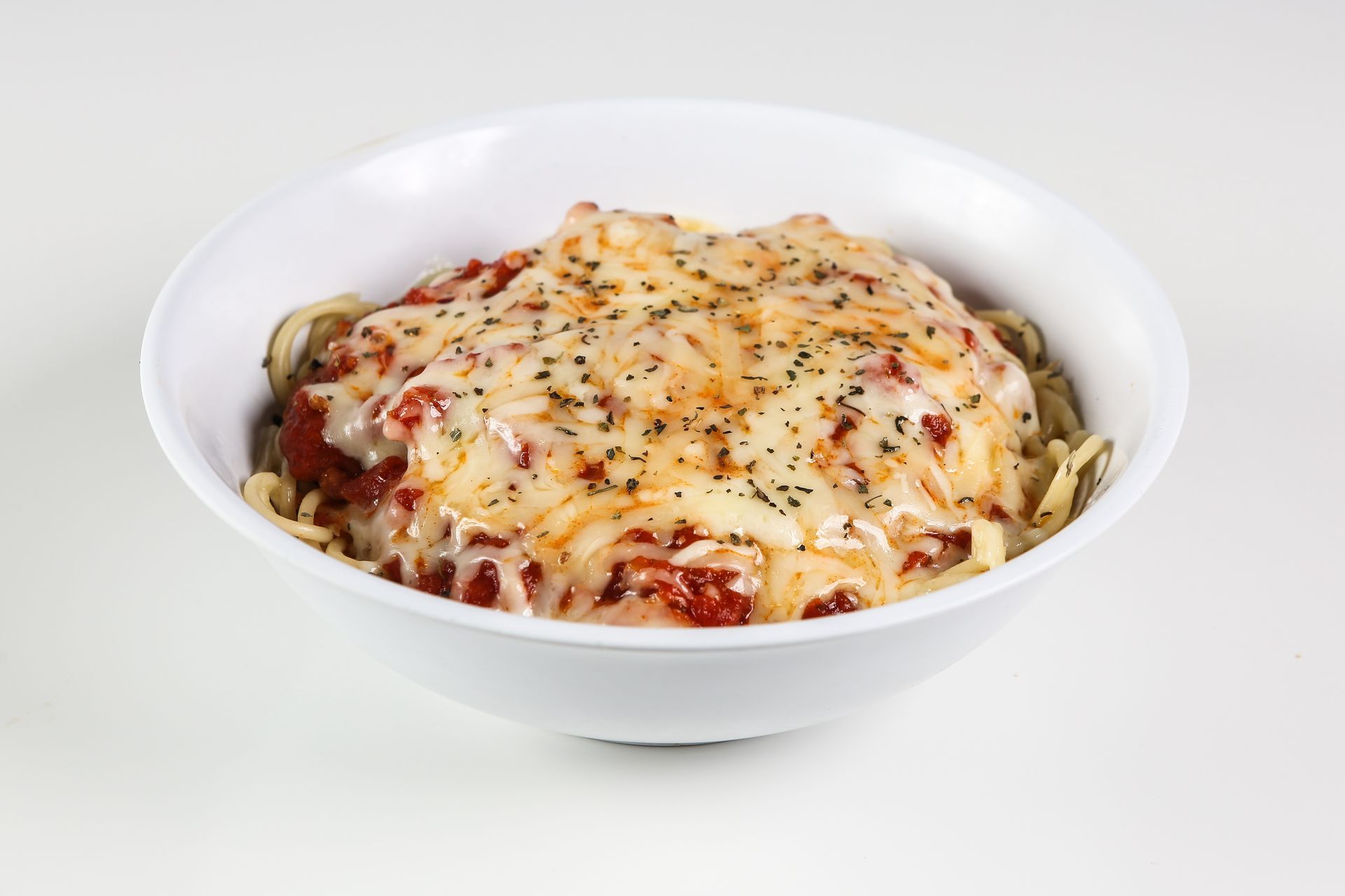 A bowl of spaghetti with tomato sauce and cheese on a table.