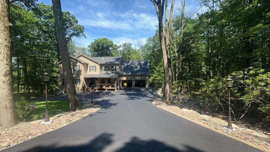 A driveway leading to a large house surrounded by trees.