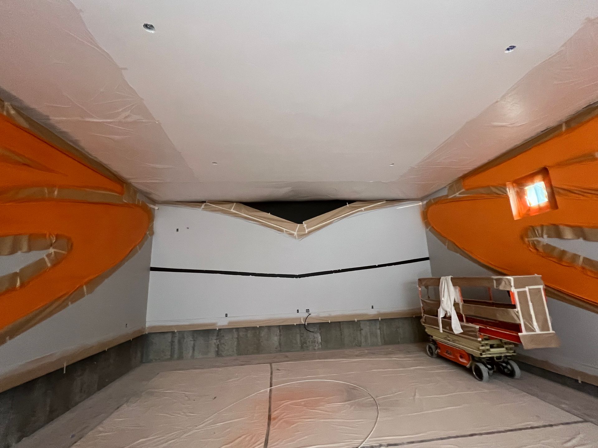 Empty modern interior with orange side walls, white ceiling, and a small cart near the back wall