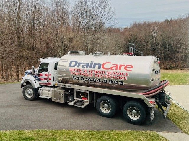 A drain care truck is parked in a driveway.