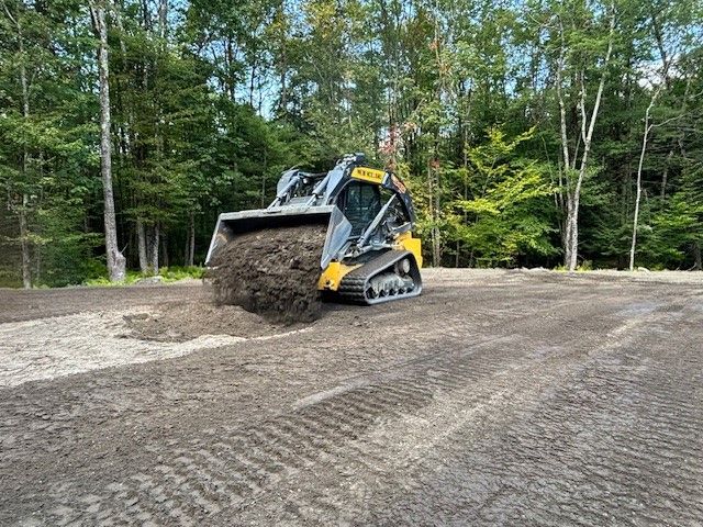 A bulldozer is spreading dirt on a dirt road.