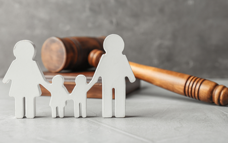 A wooden gavel is sitting next to a paper cut out of a family.