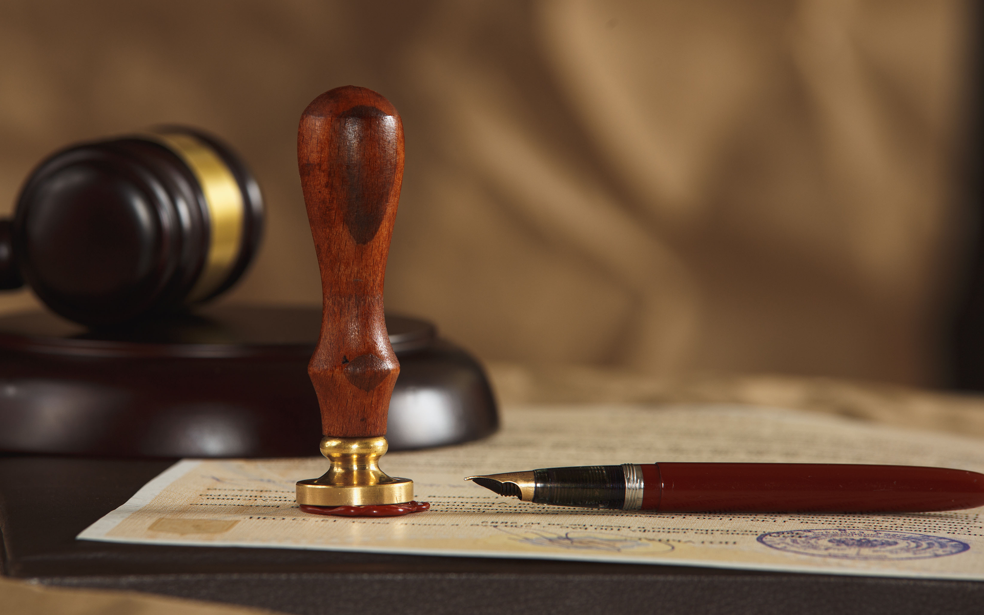 A fountain pen is sitting on top of a piece of paper next to a wooden judge 's gavel.