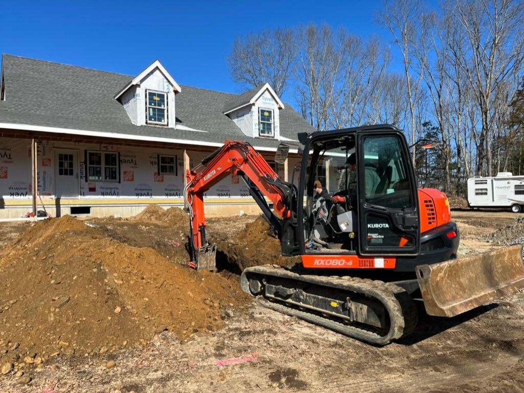 Mini excavator digging near a house under construction. Brown soil pile. Bright sunny day.