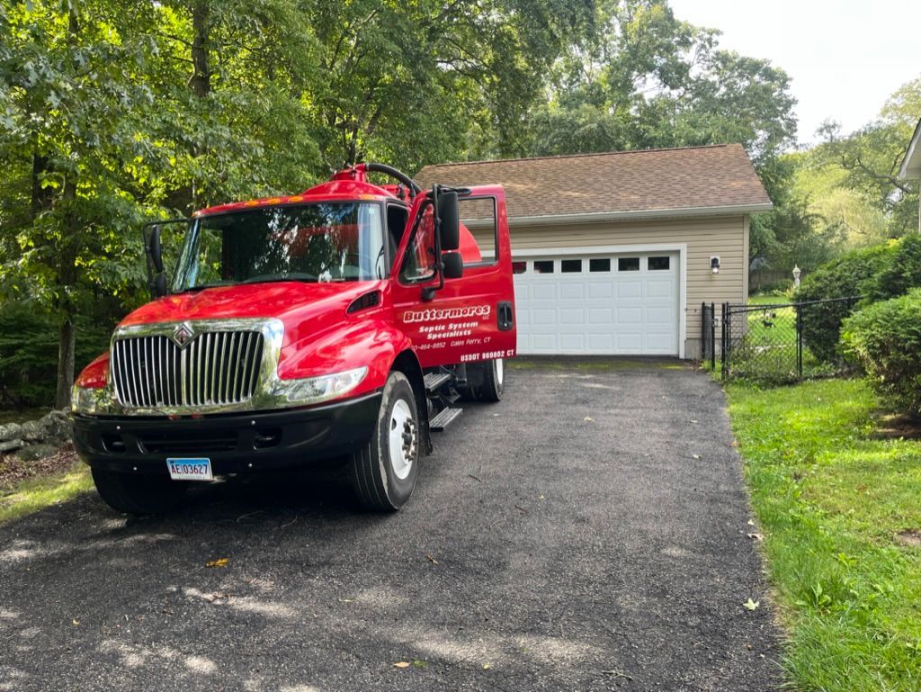 Red truck parked in driveway in front of a tan garage with a white door.