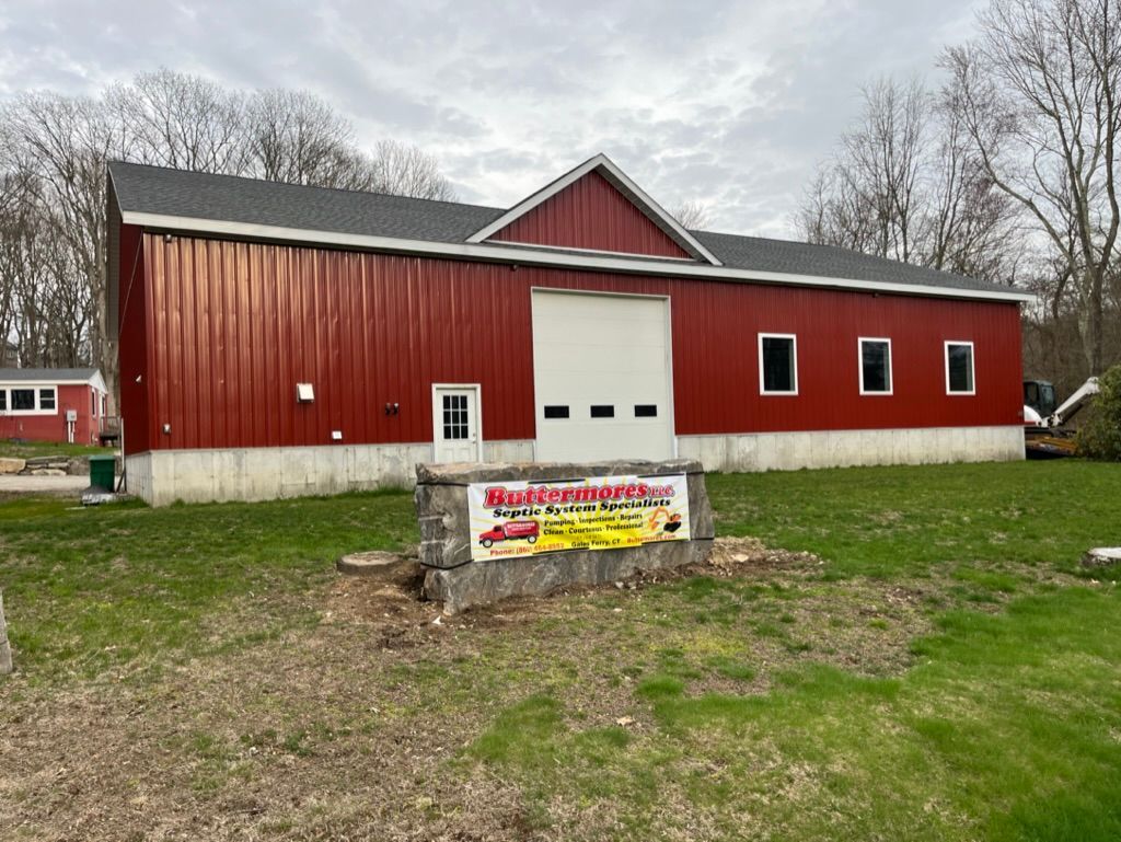 Red barn-like building with a white garage door, small windows, and a sign.