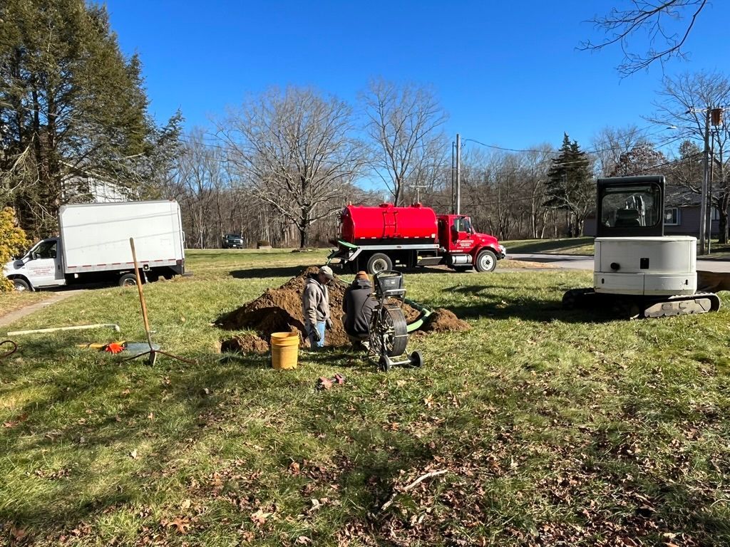 Septic tank installation on a grassy lawn with truck, workers, and machinery.