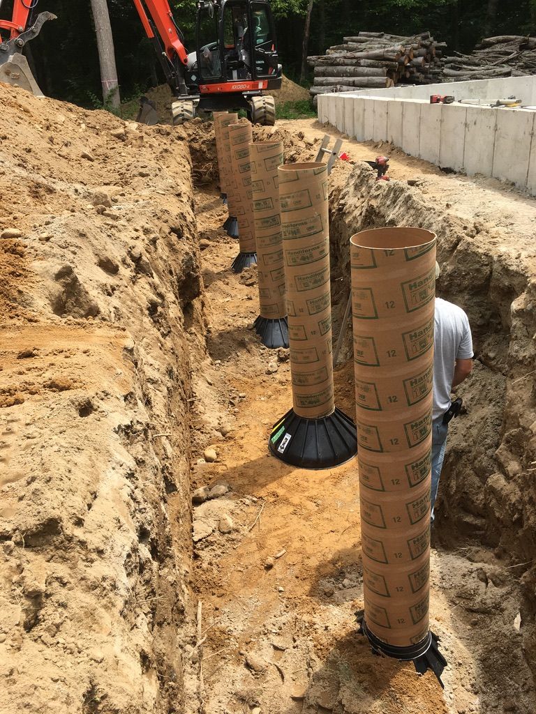 Construction site: Concrete forms in a trench, excavator in the background, person working.