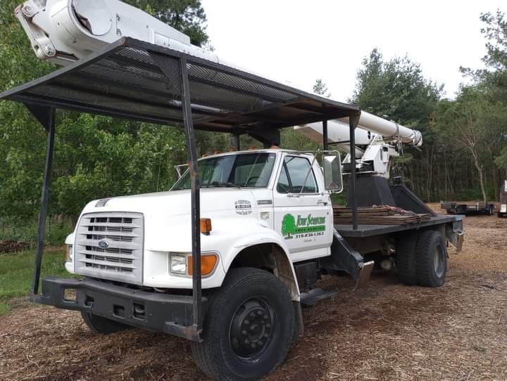 White tree service truck with a boom lift. Black canopy over the cab.