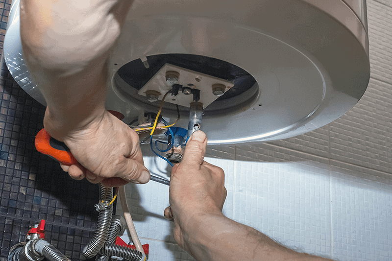 Hands working inside a ceiling light fixture, wiring exposed with tools visible