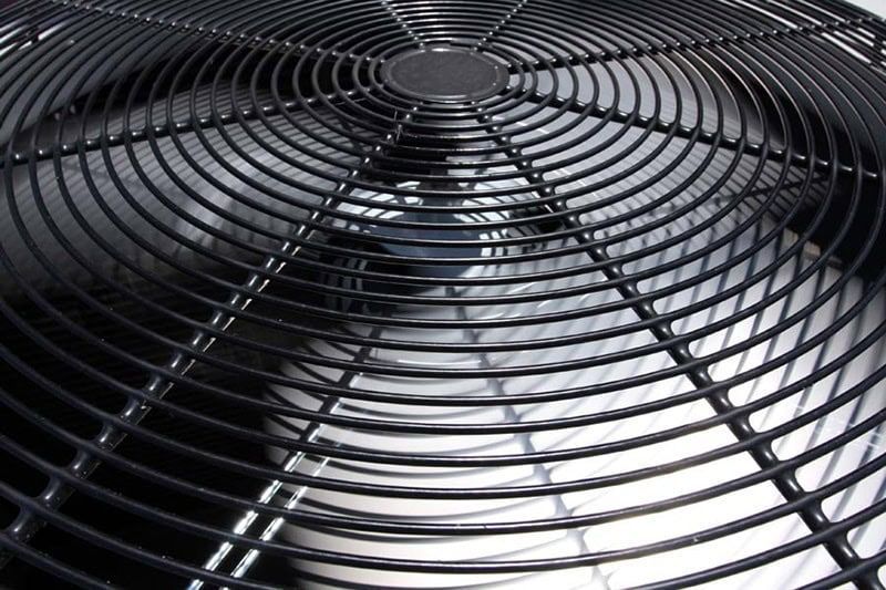 Close-up of a black metal fan grille with circular blades and radial spokes