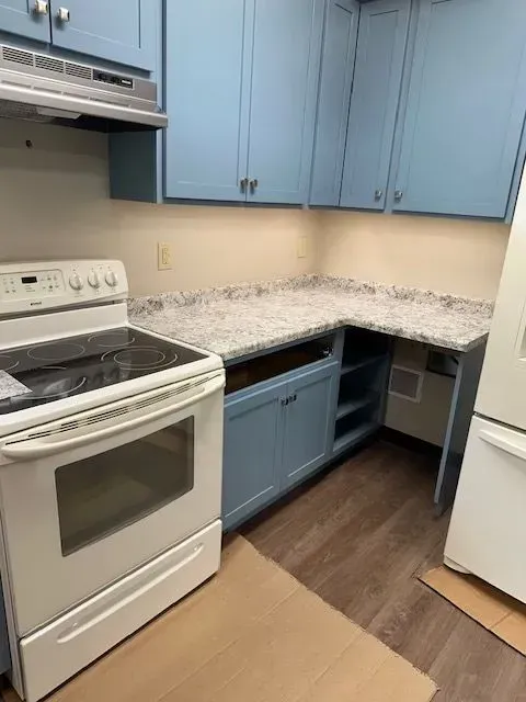 Kitchen with blue cabinets, white appliances, and gray countertops.