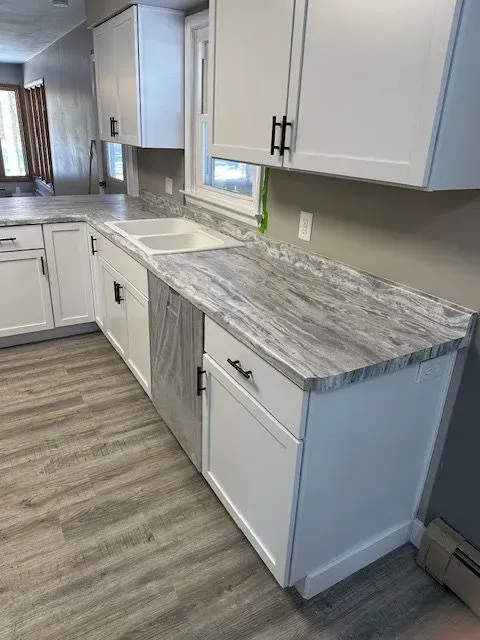 White kitchen cabinets with gray countertops and a sink.