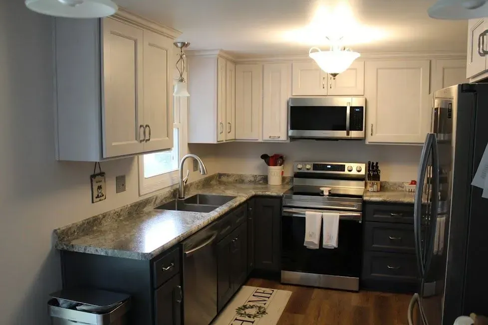 L-shaped kitchen with gray and white cabinets, stainless steel appliances, and a granite countertop.