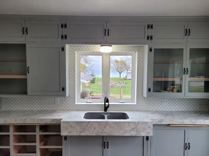 Kitchen with gray cabinets, a window over a sink, and a view of a yard.