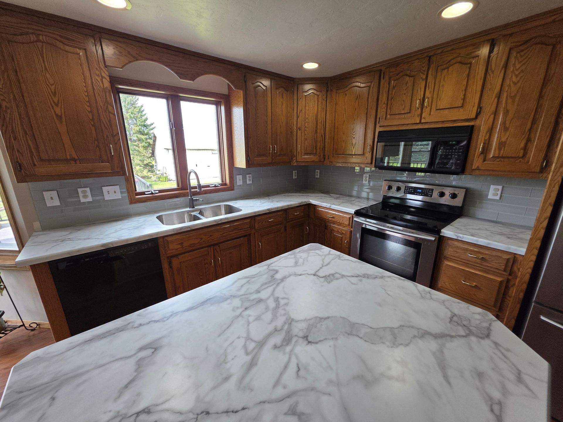 Kitchen with wooden cabinets, marble countertops, stainless steel appliances, and an island.
