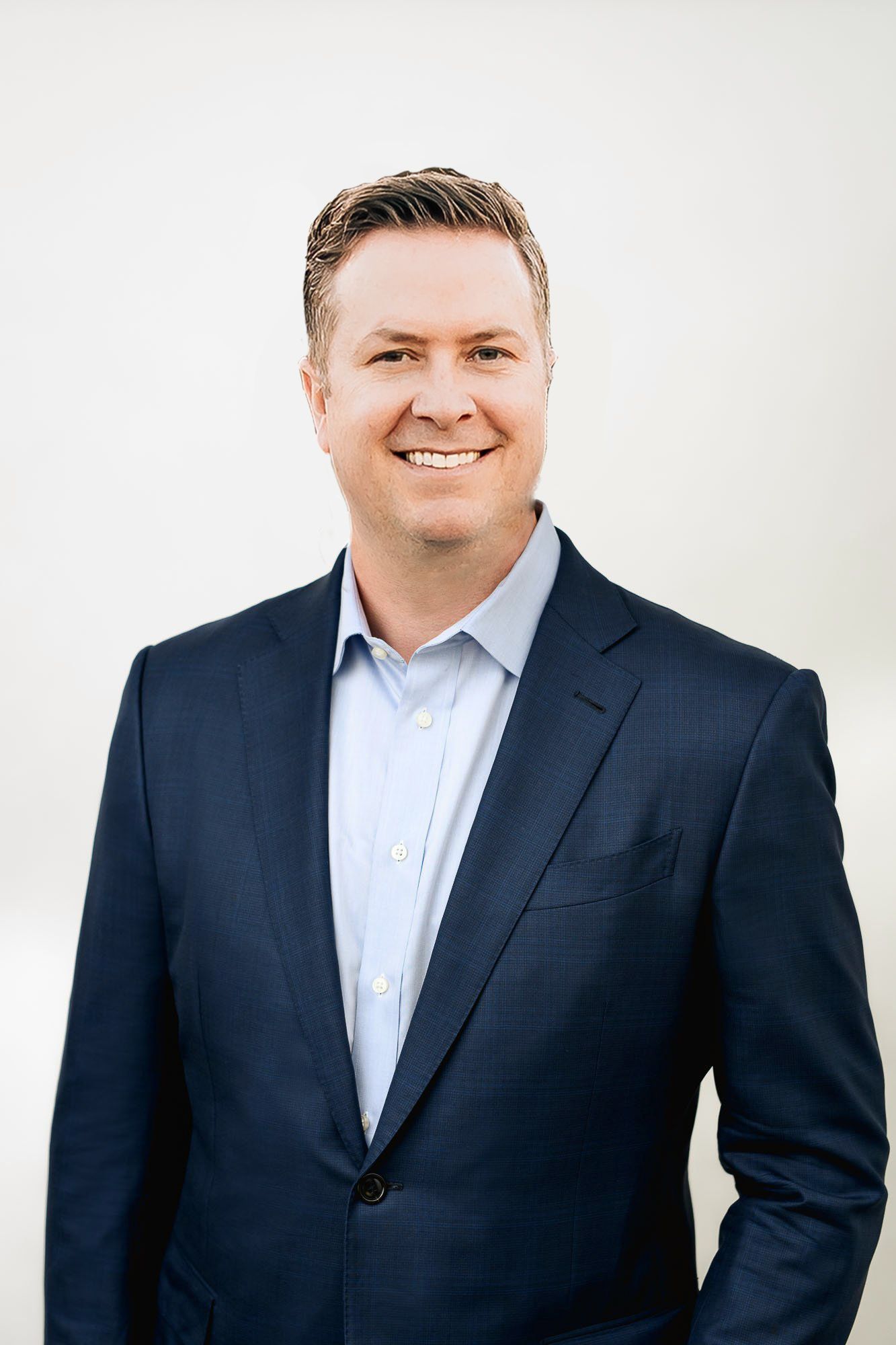 A smiling professional in a blue button-down shirt and a plaid tie, centered against a light gray background.