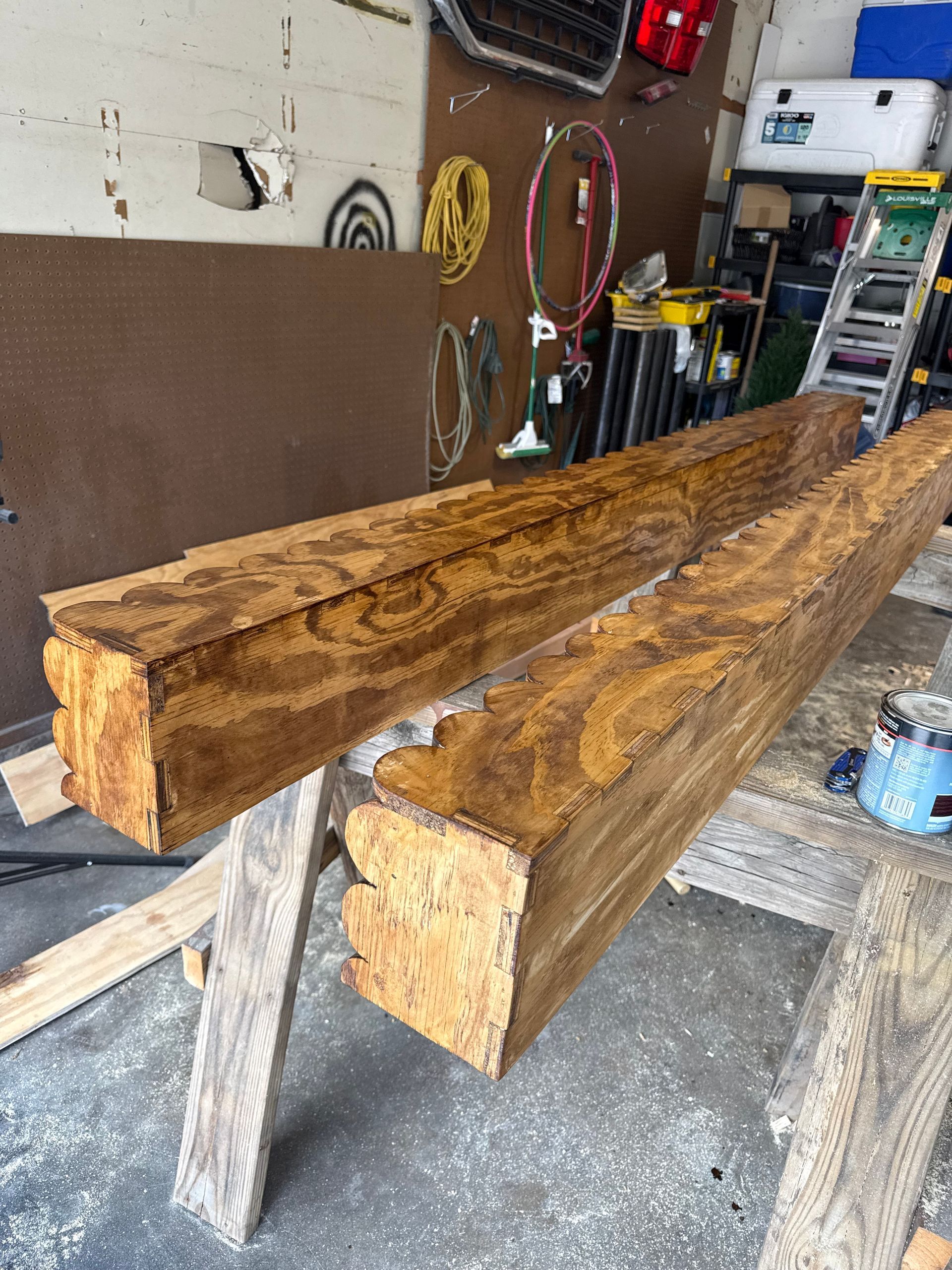 Two rough-hewn wooden beams resting on sawhorses in a workshop garage.