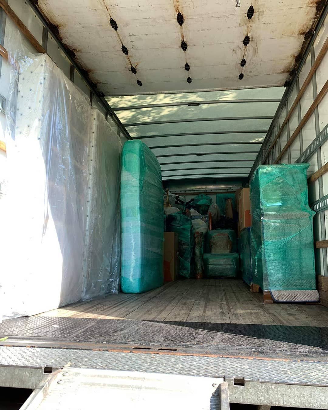 Inside a moving truck: mattresses and wrapped boxes, ready for transport.