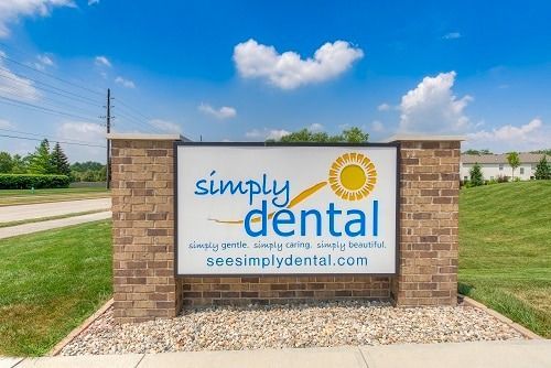 Sign for Simply Dental; brick pillars, white sign with blue text, sunny logo, and website address.