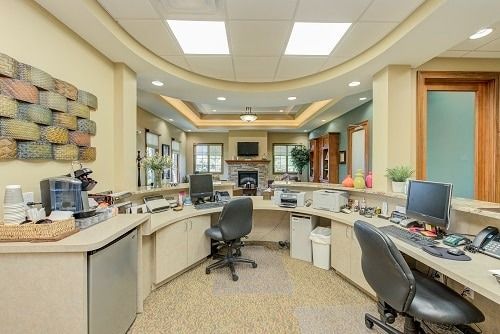 Reception area with curved counter, beige walls, computers, and chairs.