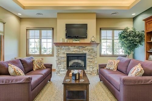 Living room with two purple sofas facing a stone fireplace and TV.
