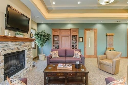 Living room: fireplace, TV, purple sofa, armchair, wooden furniture, teal walls, and a plant.