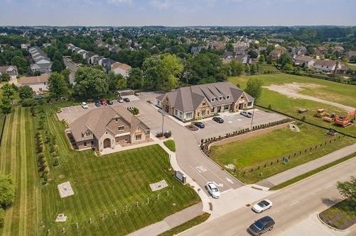 Aerial view of two tan brick buildings, one-story with dark roofs and landscaping, set in a residential area.