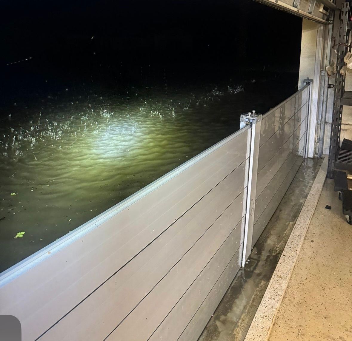 Floodlit water beside a raised metal flood barrier at night