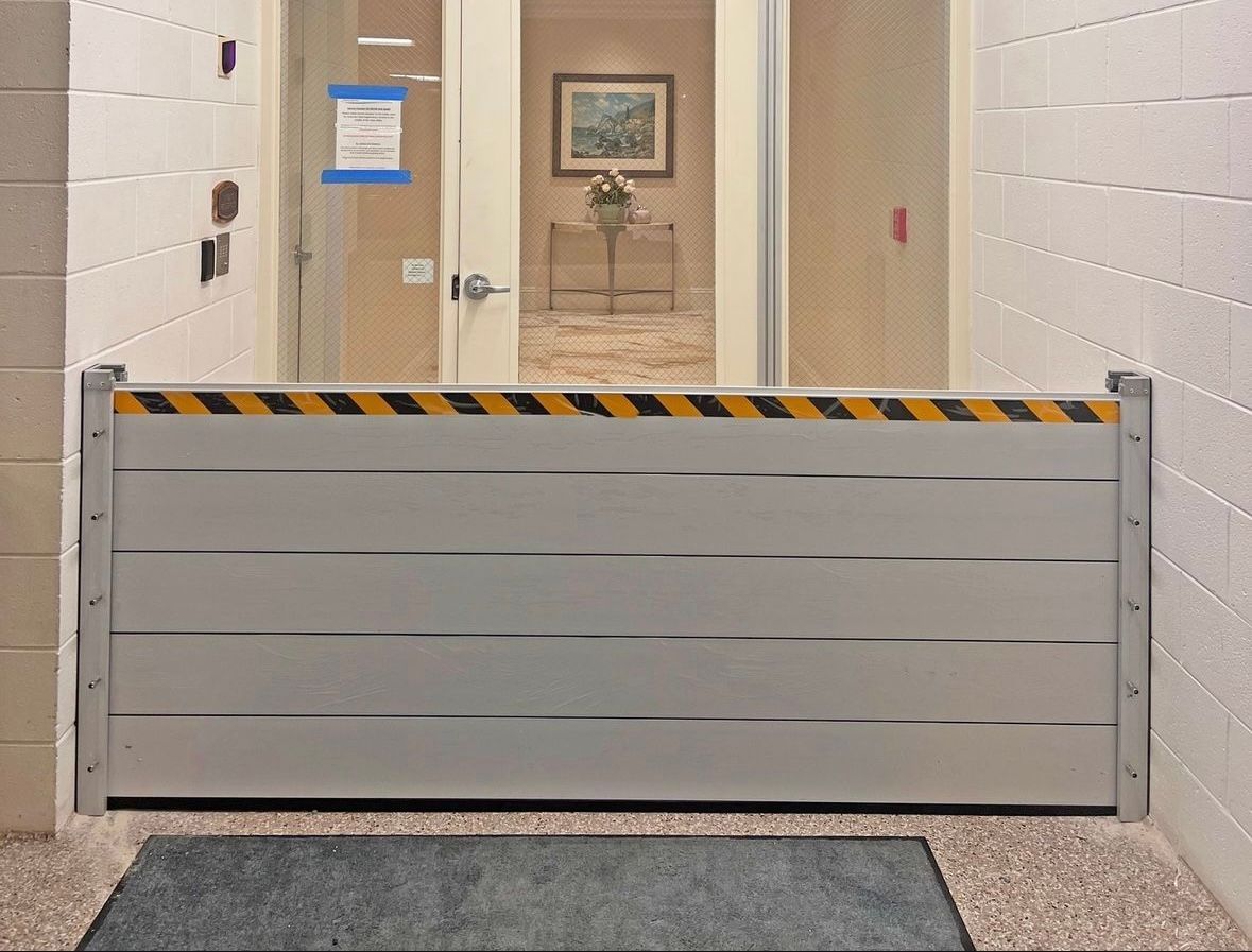Gray retractable flood barrier across a hallway entrance