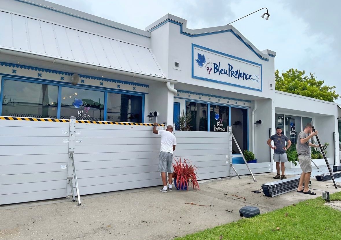 Three people outside a restaurant installing flood barriers