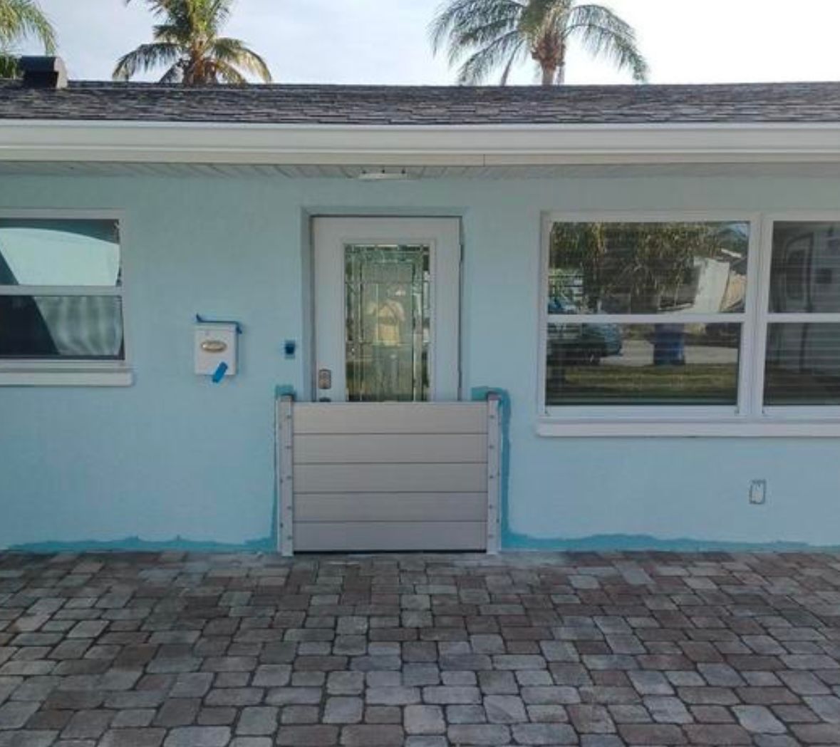 Front of a light blue house with a flood barrier in front of a door