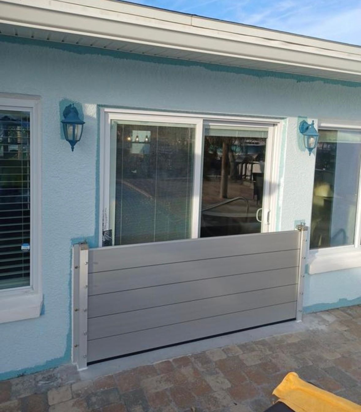 A light blue house with a flood barrier in front of a sliding door