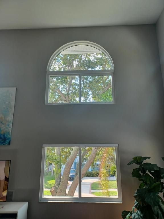 Tall wall with arched and rectangular windows showing trees and a bright outdoor view