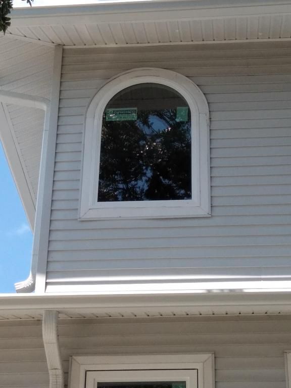 Arched second-story window on a light gray house exterior