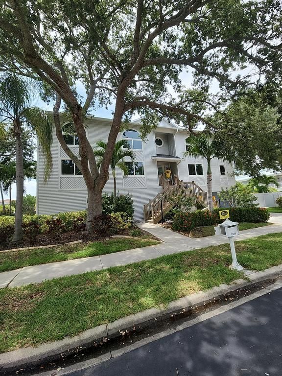 White two-story house with front steps and large trees