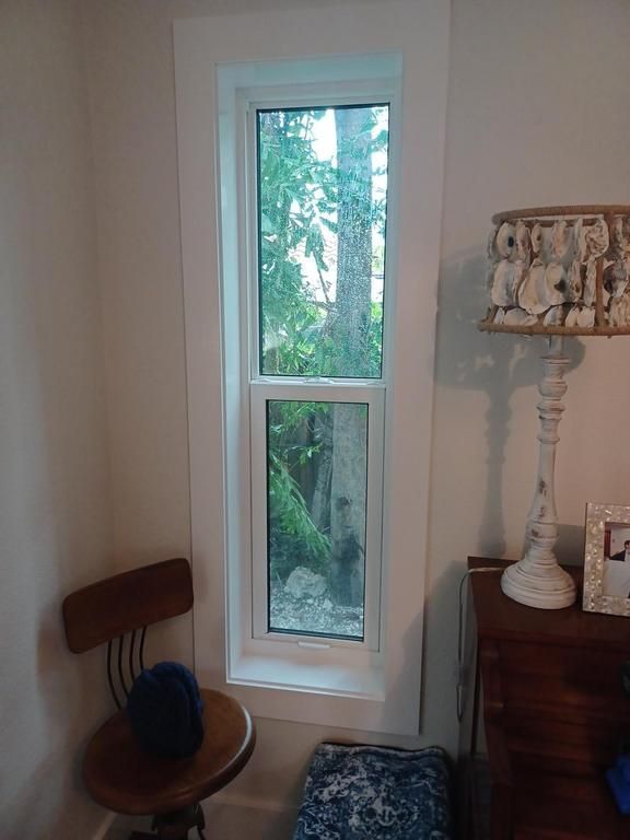 Narrow window beside wooden chair and sideboard