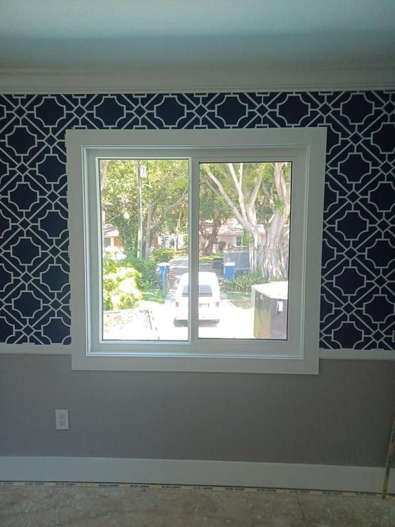 Interior wall with blue patterned wallpaper and a white window